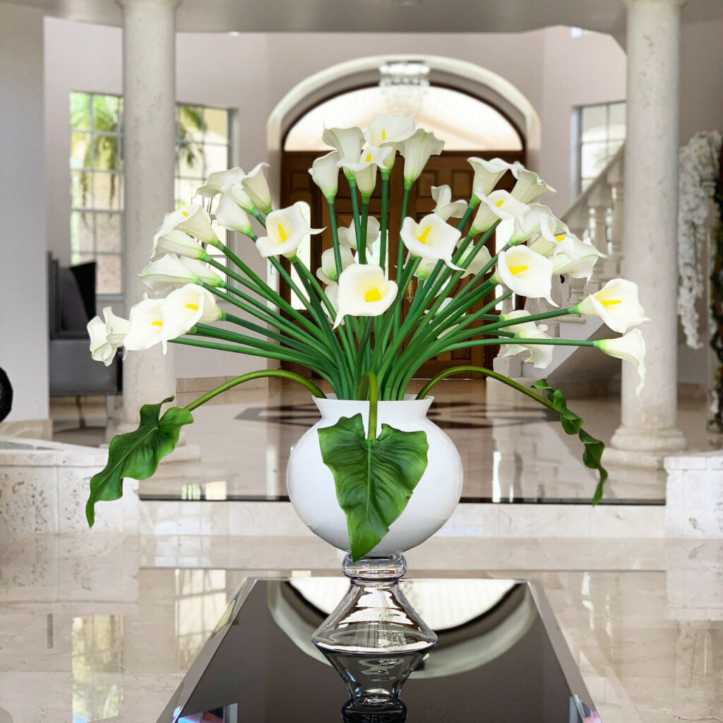 Vase élégant avec plusieurs lys calla blancs.