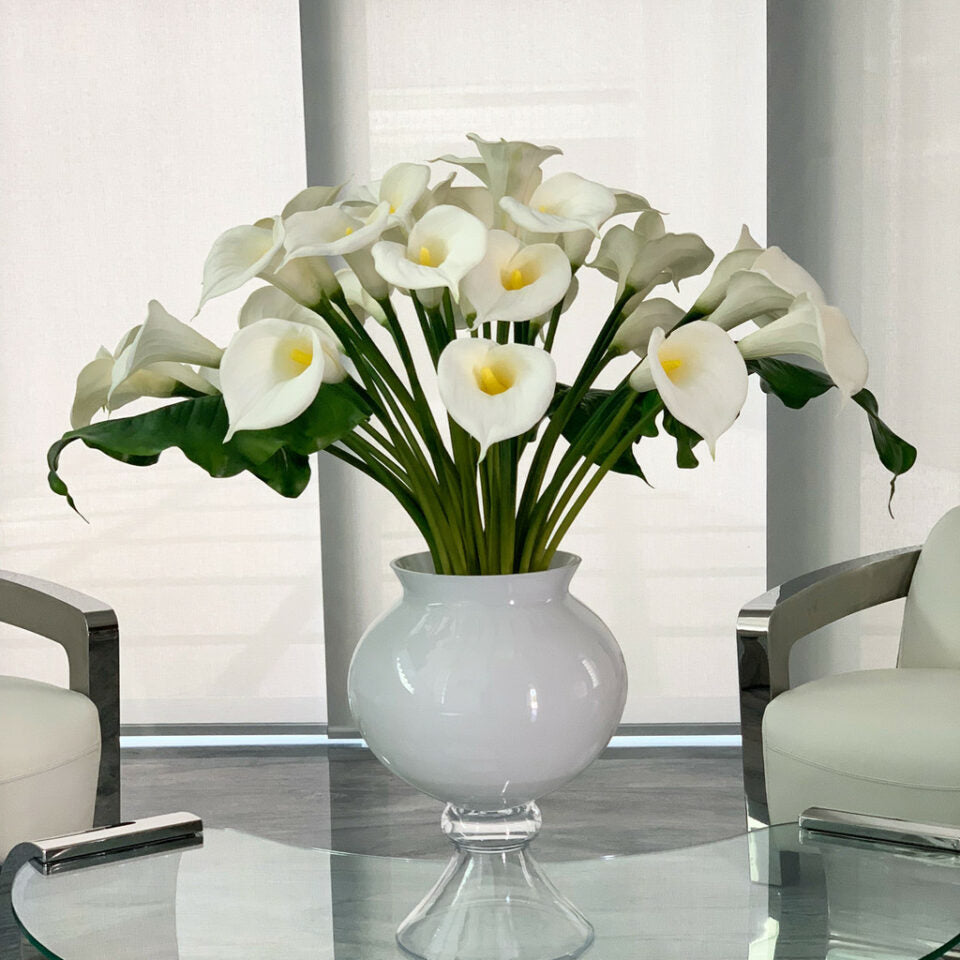 Vase élégant avec plusieurs lys calla blancs.