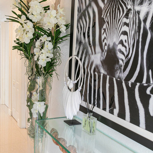 Orchidées Vanda blanches et bois flotté à l'intérieur d'un grand cylindre conique en verre.