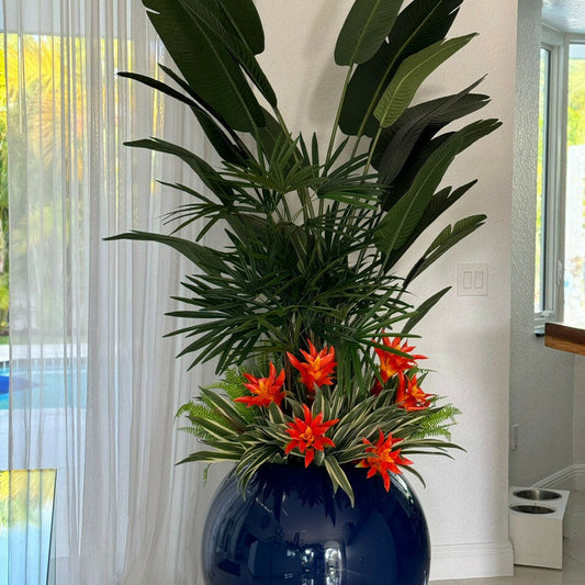 Mélange de plantes tropicales dans un pot sphérique bleu cobalt.